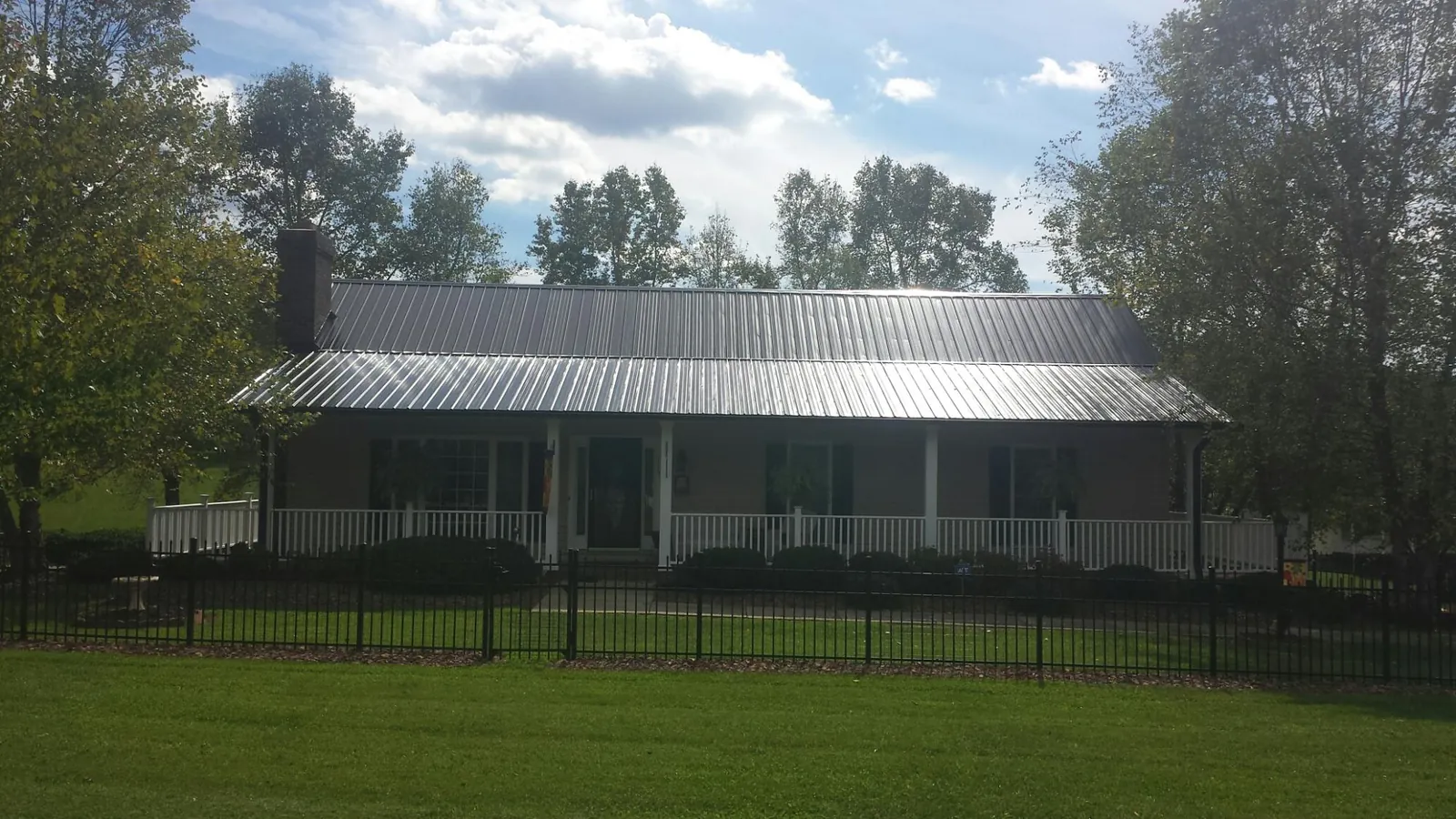 Gray metal roof on a brick ranch with a full width front porch — Gutter Guard Installation work by our crew in Germantown
